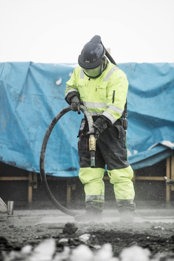 Construction worker operating heavy machinery at a building site, ensuring safety and precision.